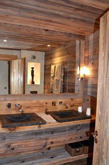 a modern rich-stained bathroom clad with wood, with a large mirror, a double vanity with open shelves and lights