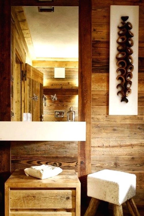 a light-stained wood chalet bathroom completely covered with wood, with a modern sink, a mirror and a white pouf