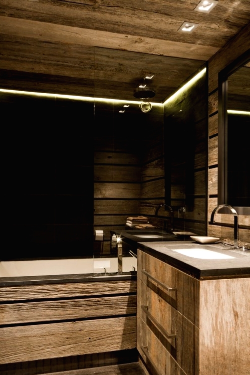 a contemporary chalet bathroom with light-stained wood all over, with black tiles, built-in lights and a floating vanity