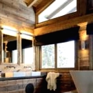 a beautiful chalet bathroom clad with white stone and rich-stained wood, with a floating vanity and a large bathtub is amazing