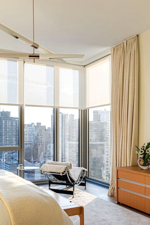 a refined modern bedroom with a fantastic view, with semi sheer shades and beautiful neutral draperies to enjoy the views or get privacy when needed