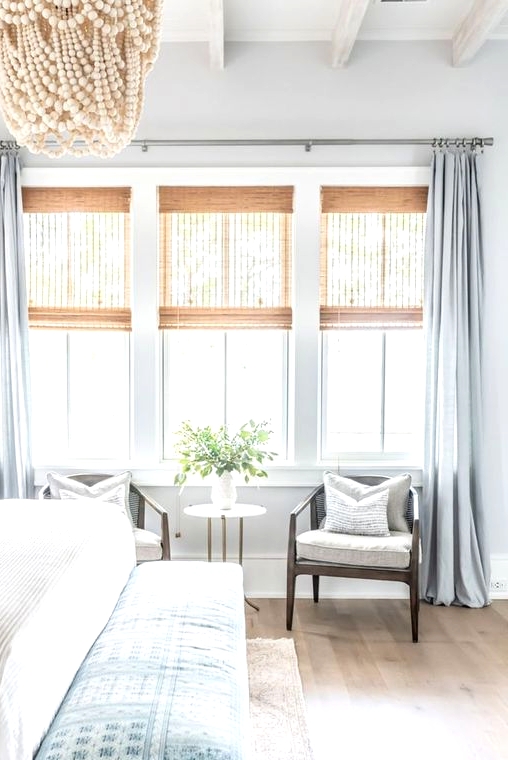 semi sheer woven shades and pastel blue curtains are a perfect match for a coastal bedroom done in the same pastel blues