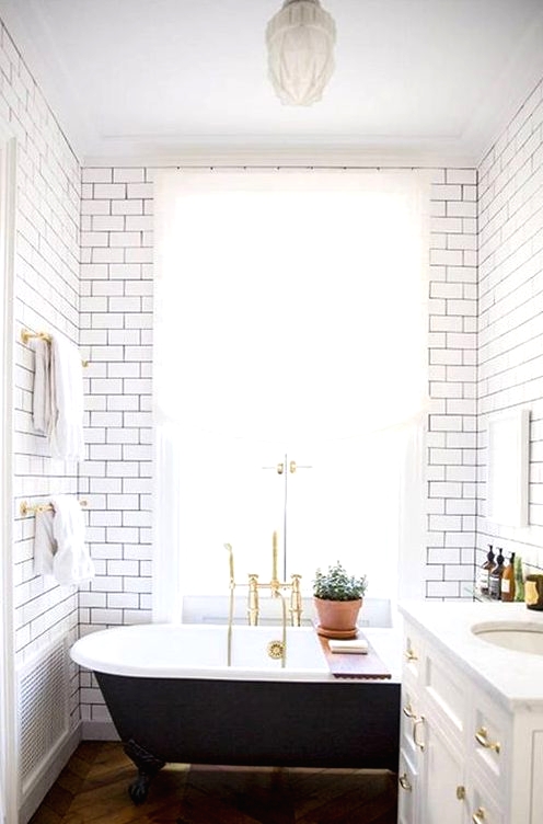a vintage black clawfoot bathtub and black grout with subway tiles bring more chic to the space