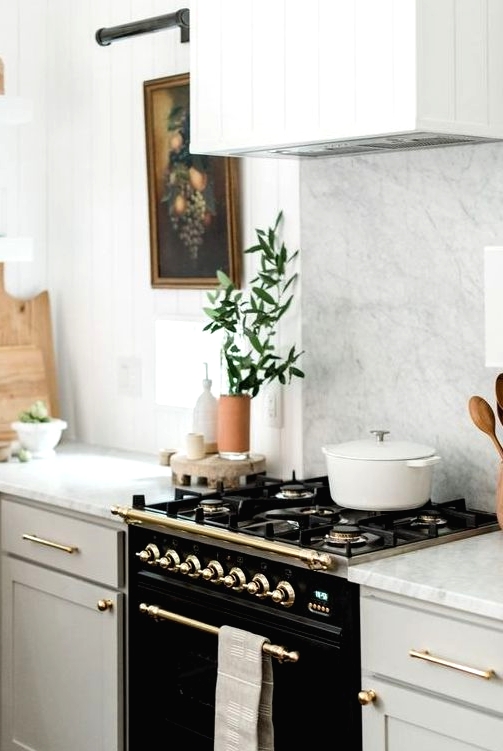 an elegant black cooker and some gold touches add drama and chic to the neutral kitchen with a vintage feel