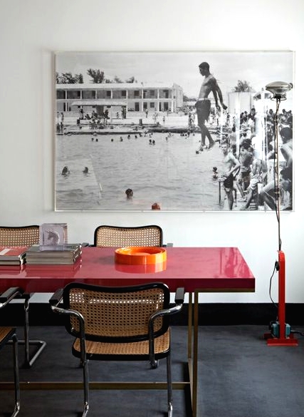 a chic space that pairs up a modern red table and vintage rattan chairs to make the look incredibly bold