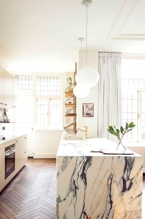 a chic modern kitchen in white and a white marble kitchen island, gold fixtures for a more glam look