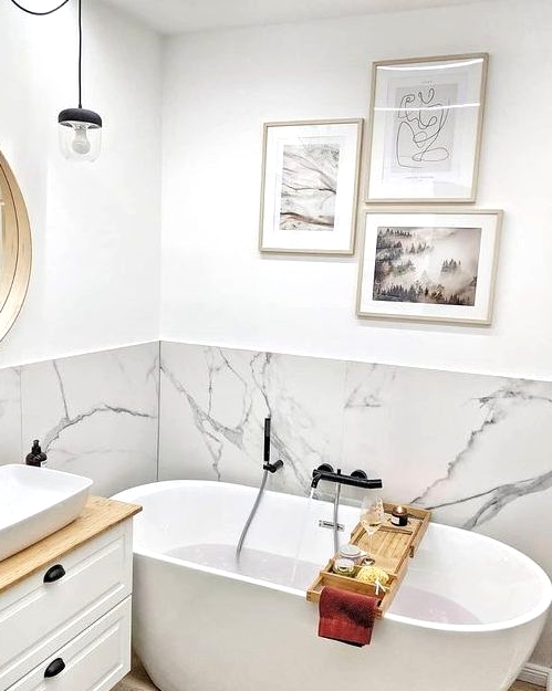 a small contemporary bathroom with a white marble backsplash and white furniture plus a gallery wall