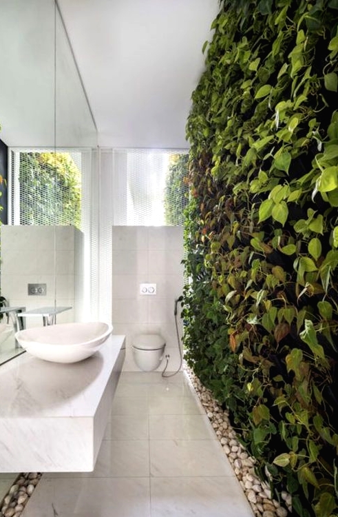a truly biophilic bathroom done in neutrals and with a living wall and pebbles on the floor for a natural touch