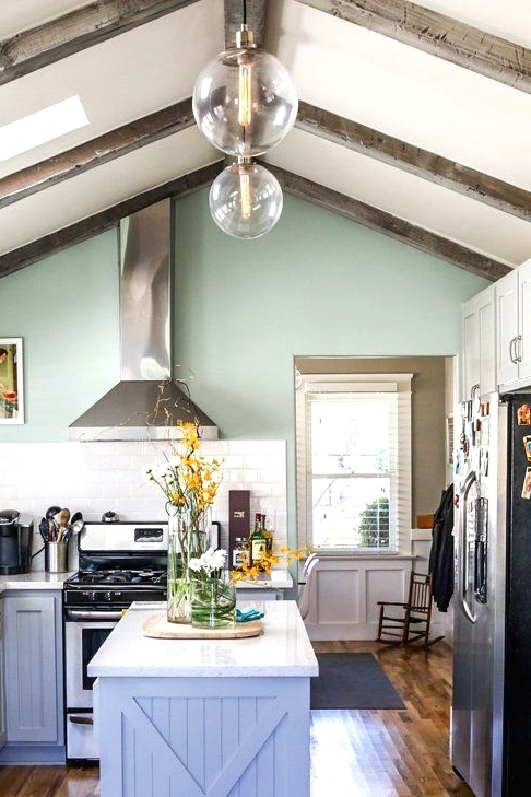 a cottage very peri kitchen with white countertops, white subway tiles, wooden beams on the ceiling and stainless steel appliances
