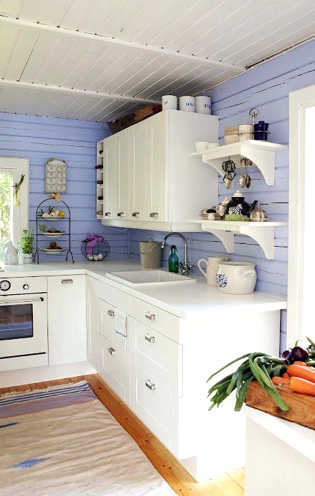 a pretty and chic kitchen with very peri planked walls, creamy cabinets, a dip-dyed rug looks very cute and cottage-like