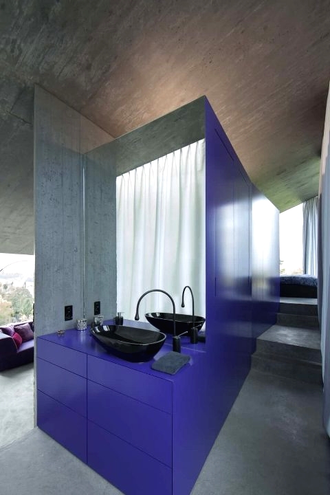 a bathtoom cluster completely hidden with bold periwinkle panels, a black sink, a black faucet and neutral curtains