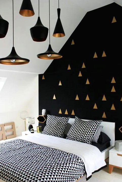 a gorgeous black and gold geometric pattern accent wall plus black and brass pendant lamps that echo with it