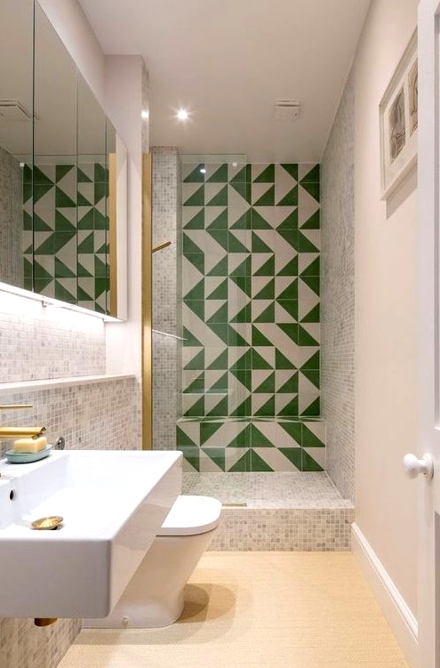 a neutral bathroom with small scale tiles, a green and white tile wall in the shower space, white applainces and brass touches