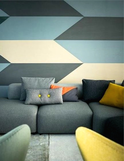 a muted color living room with a cool geo accent wall, a grey sofa, yellow and grey chairs is a chic idea
