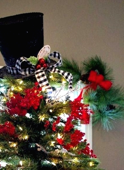 a black top hat with a plaid ribbon, and berries plus lots of red faux berries accenting the tree make it bold and fun and the tree topper adds a touch of whimsy