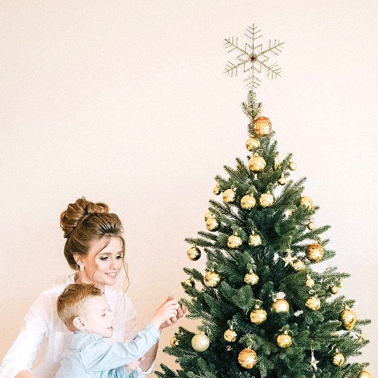 a glam Christmas tree with gold baubles and stars and a delicate gold snowflake tree topper that looks cool
