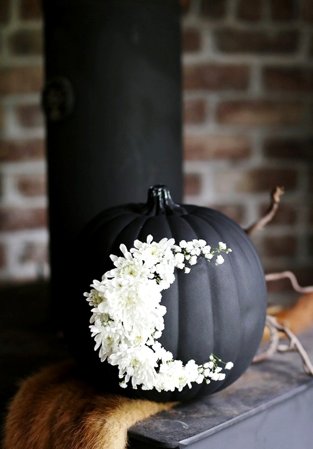 Painted black pumpkin decorated with fresh flowers.